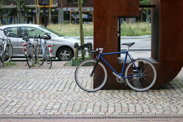Photo by Sebastian A blue fixie bike parked on a cobblestone street in an urban setting, showcasing city life.