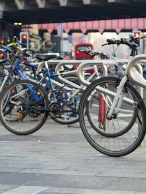 A vibrant city street scene featuring parked bicycles along a busy urban sidewalk.