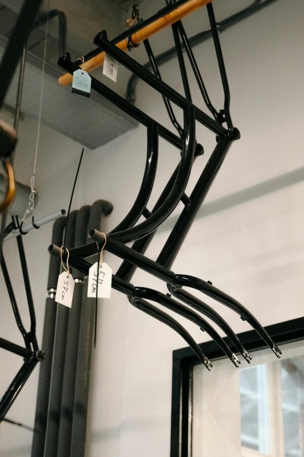 Photo by Mathias Reding Hanging black steel bicycle frames in an Amsterdam workshop with natural lighting.